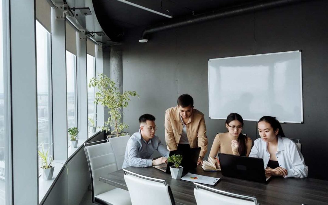 Stack of business laptops on an office conference table grouped for collection, representing end-of-lease IT equipment return and data destruction compliance