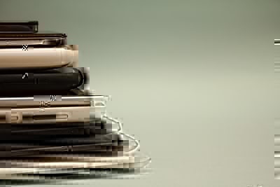 A mixed pile of smartphones and tablets on an industrial surface, representing mobile device e-waste and ITAD disposal
